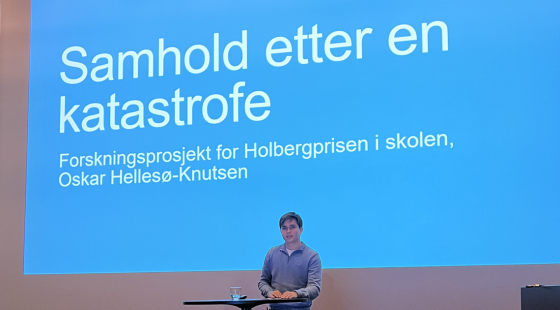 Oscar Hellesø-Knutsen presenterer med powerpoint i bakgrunnen.